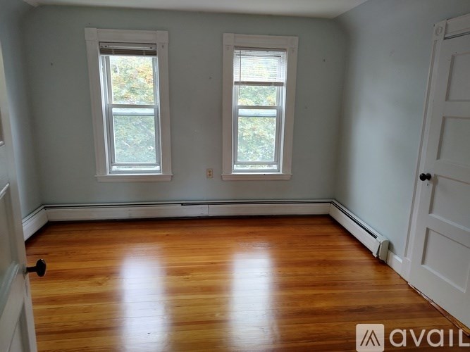 A room with wooden floors and two windows.
