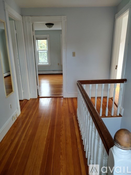 A long hallway with wood floors and white walls.