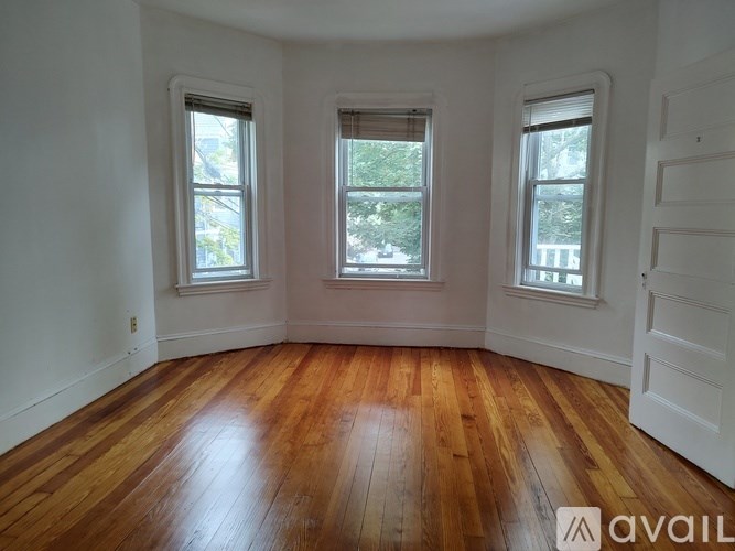 A room with wooden floors and three windows.