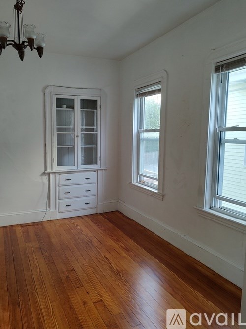 A room with a chandelier, a window, and a wooden floor.