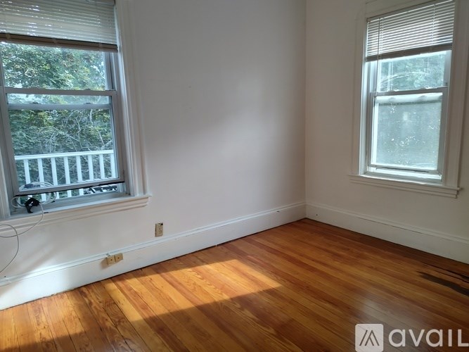 A room with wooden floors and two windows.