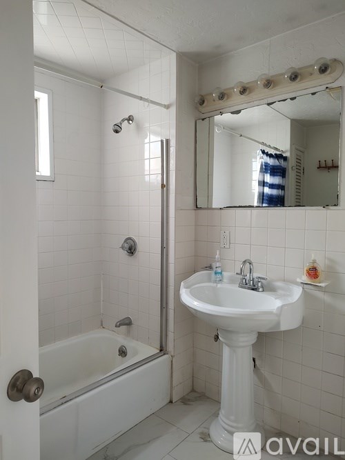 A white bathroom with a sink, mirror, and bathtub.