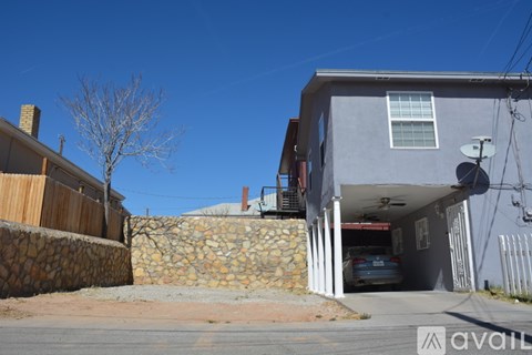 A house with a stone wall and a car in the garage.