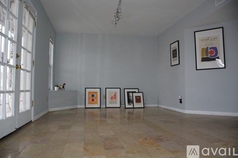 A room with a white wall and a tiled floor with three framed pictures on it.