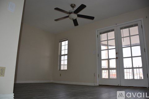 A room with a ceiling fan and two windows.