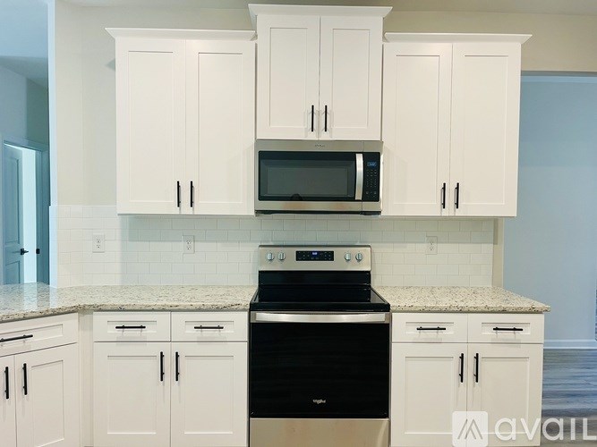 A kitchen with white cabinets and a black stove top oven.