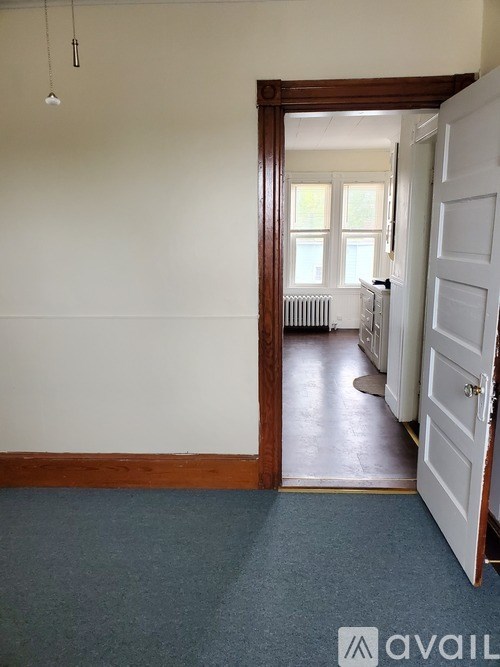 A room with a white wall and a door leading to another room.