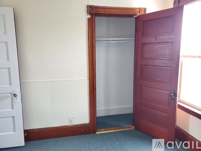 A room with a white door, a red door, and a window.