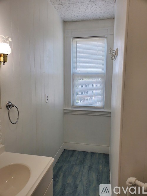 A bathroom with a white sink and a window with blinds.