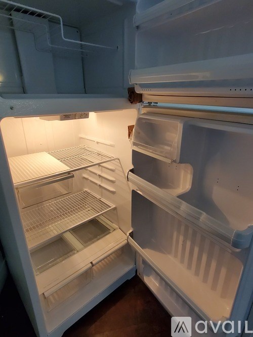 Empty white refrigerator with the door open.