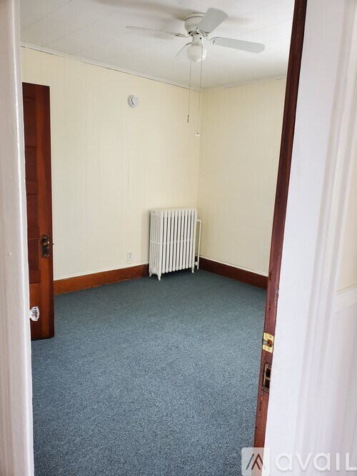 A room with a fan, a radiator, and a door.
