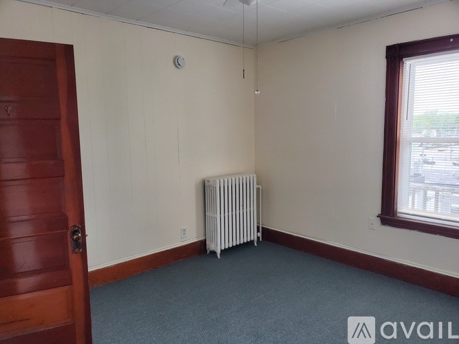 A room with a door, a window, and a radiator.