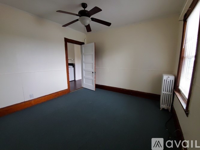 A room with a ceiling fan and a window with a white fan heater.