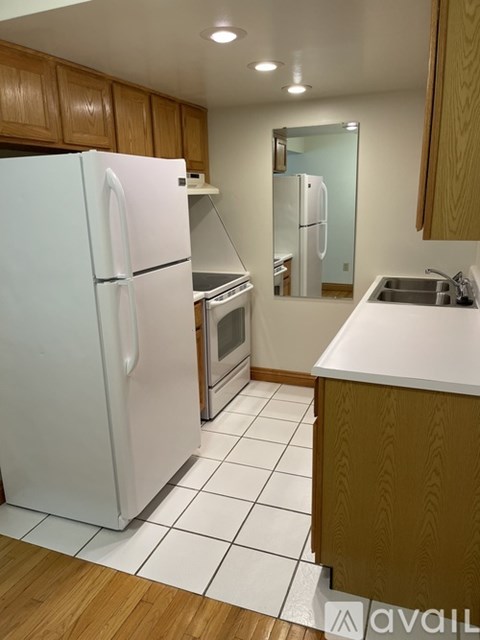 A white refrigerator in a kitchen with wooden cabinets.