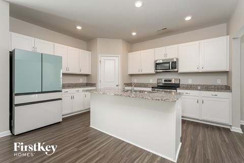 A kitchen with a white island and a refrigerator with a glass door.