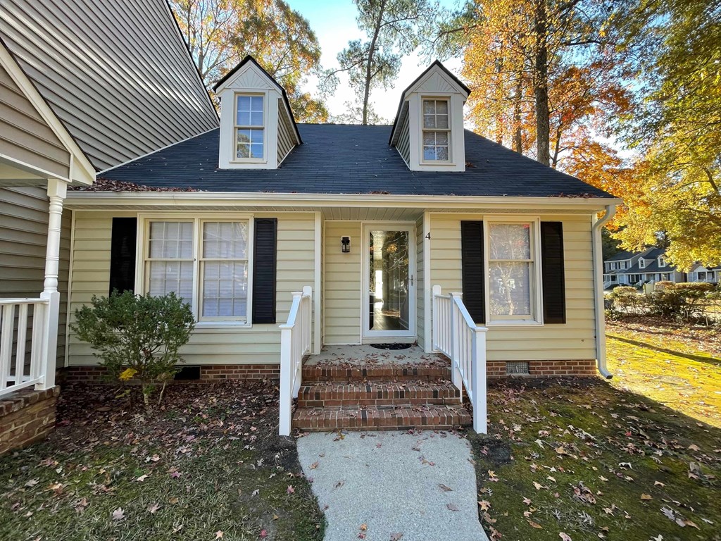 A small house with a front porch and a small tree in front.