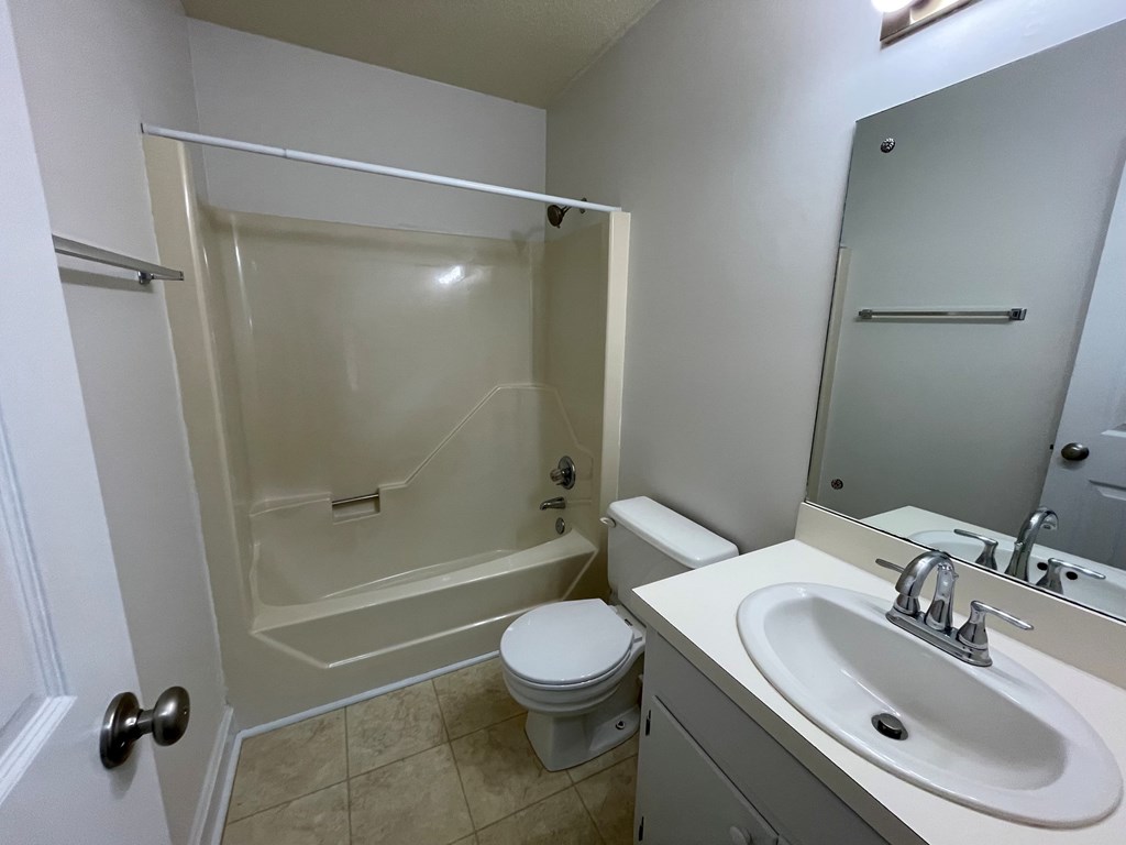 A white bathroom with a toilet, sink, and shower.