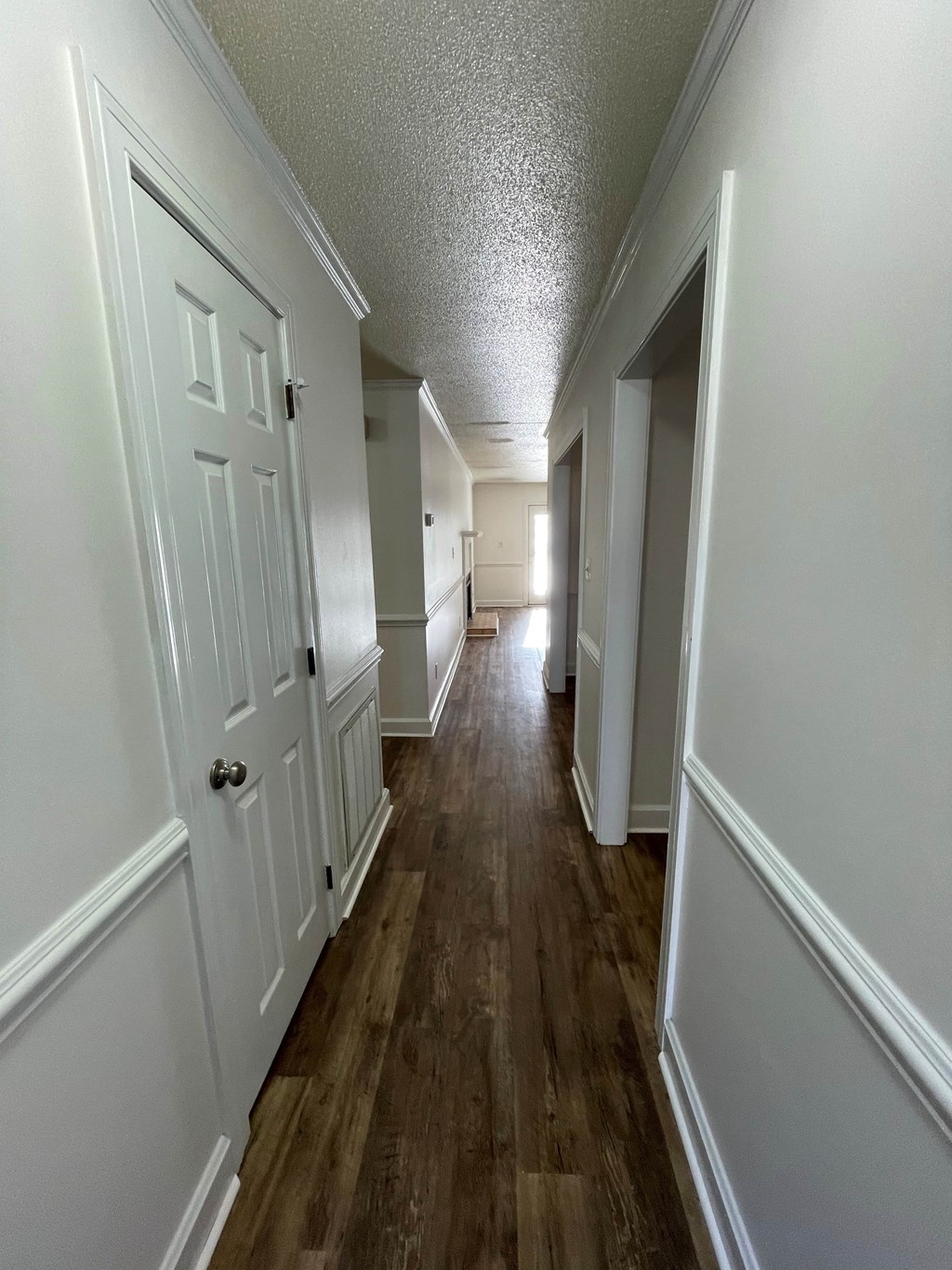 A long hallway with white doors and wood floors.