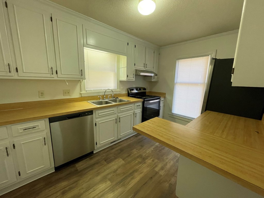 A kitchen with white cabinets and a wooden counter.