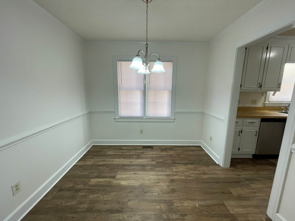 A room with wooden flooring and a window with blinds.