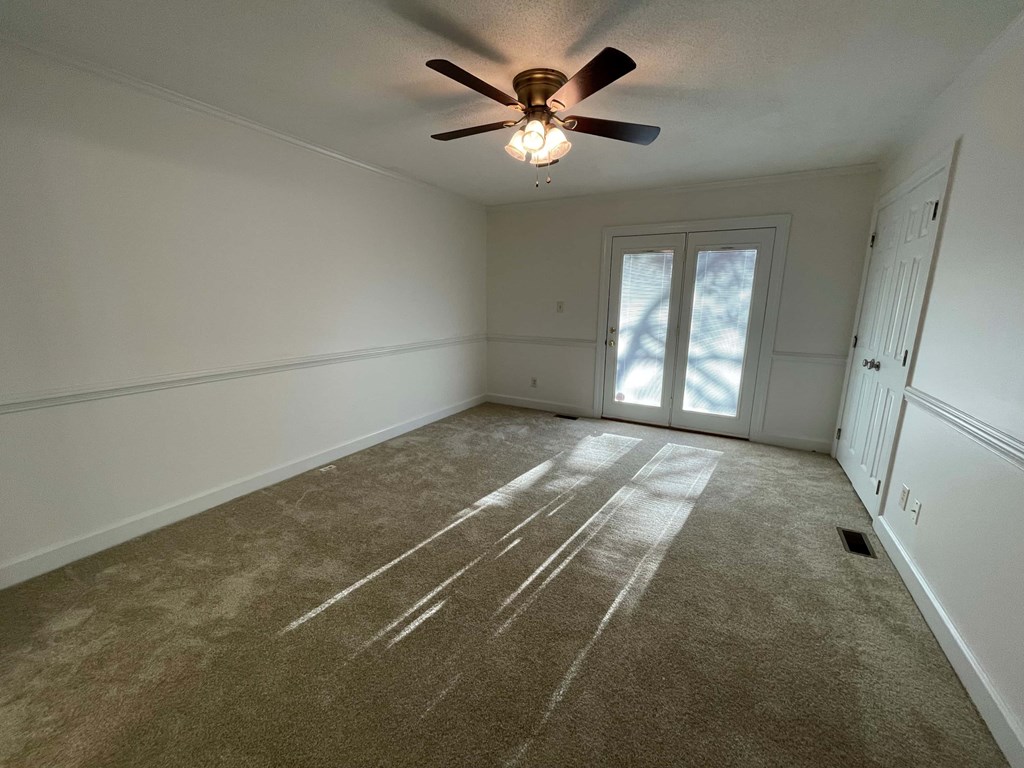 A room with a ceiling fan and carpeted floor.