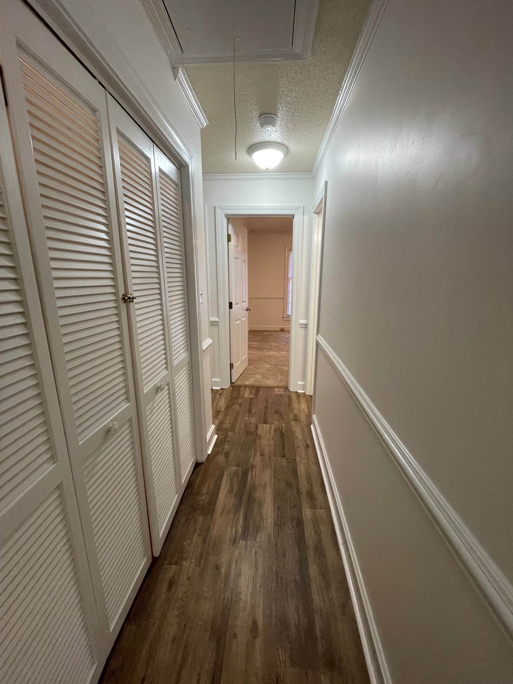 A long hallway with white walls and wood floors.