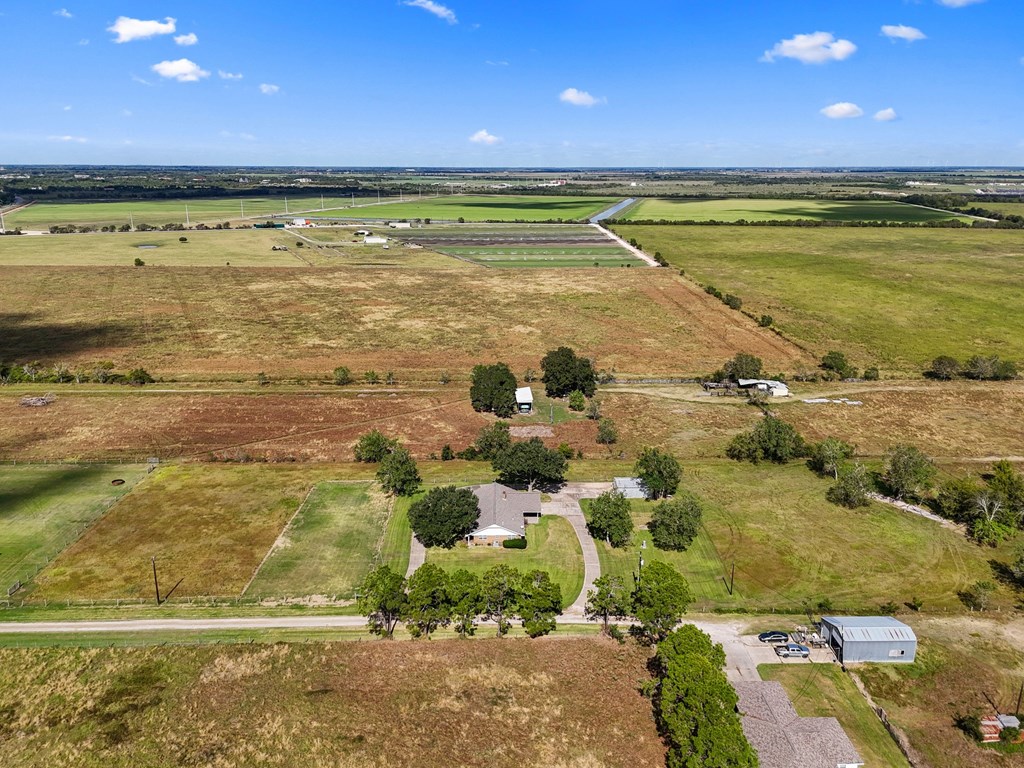 A large open field with a few buildings and trees scattered around.