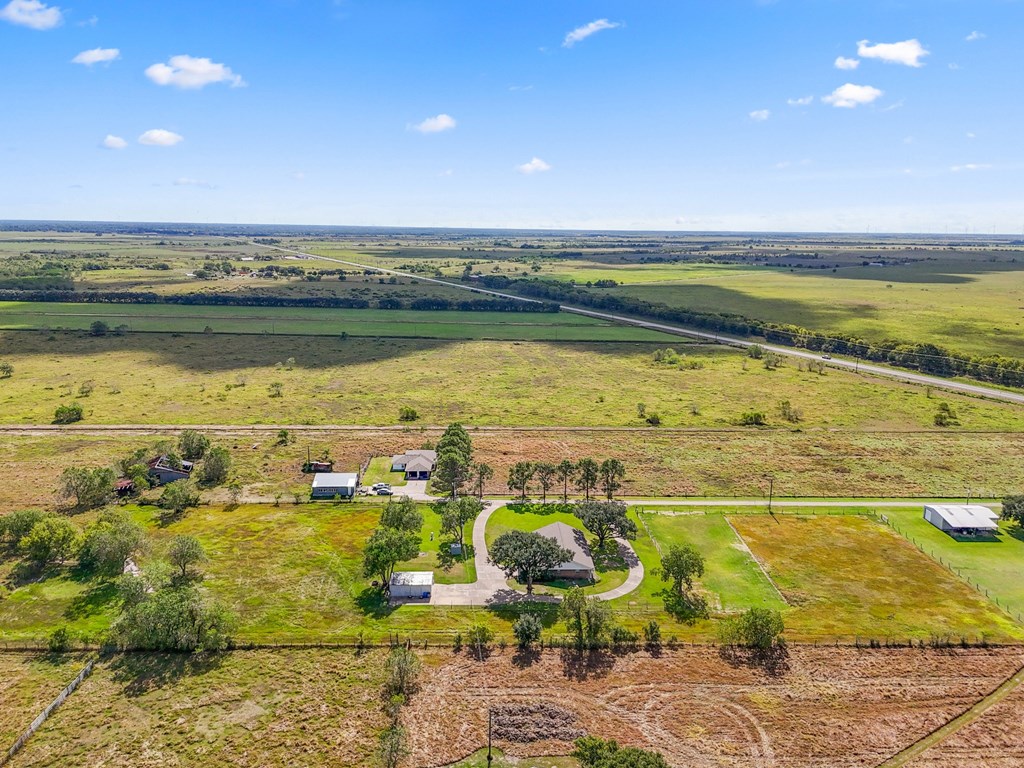 A rural landscape with a few buildings and a road.