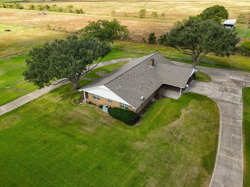 A house with a grey roof is surrounded by a green lawn.
