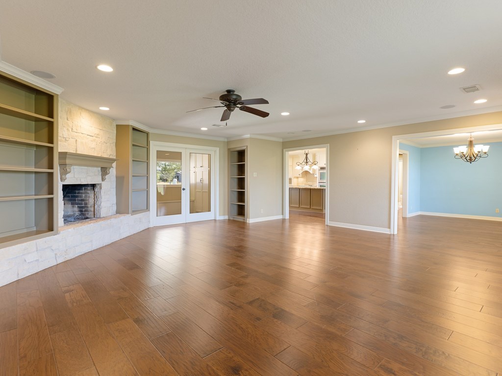 A spacious room with wooden floors and a ceiling fan.