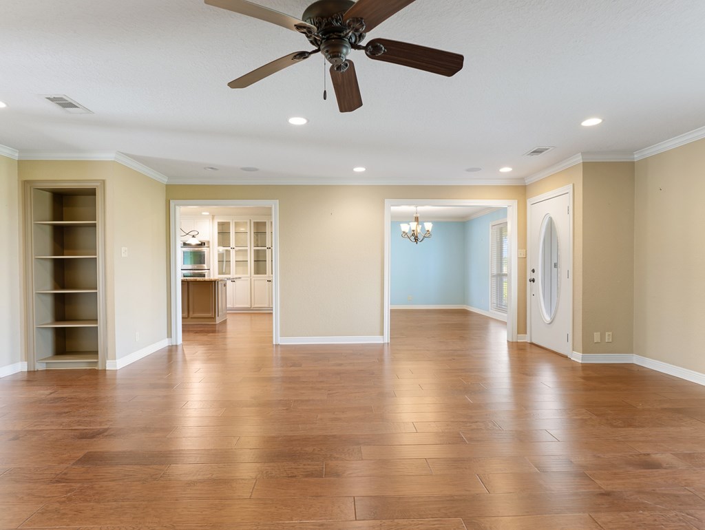 A room with a ceiling fan and wooden floors.