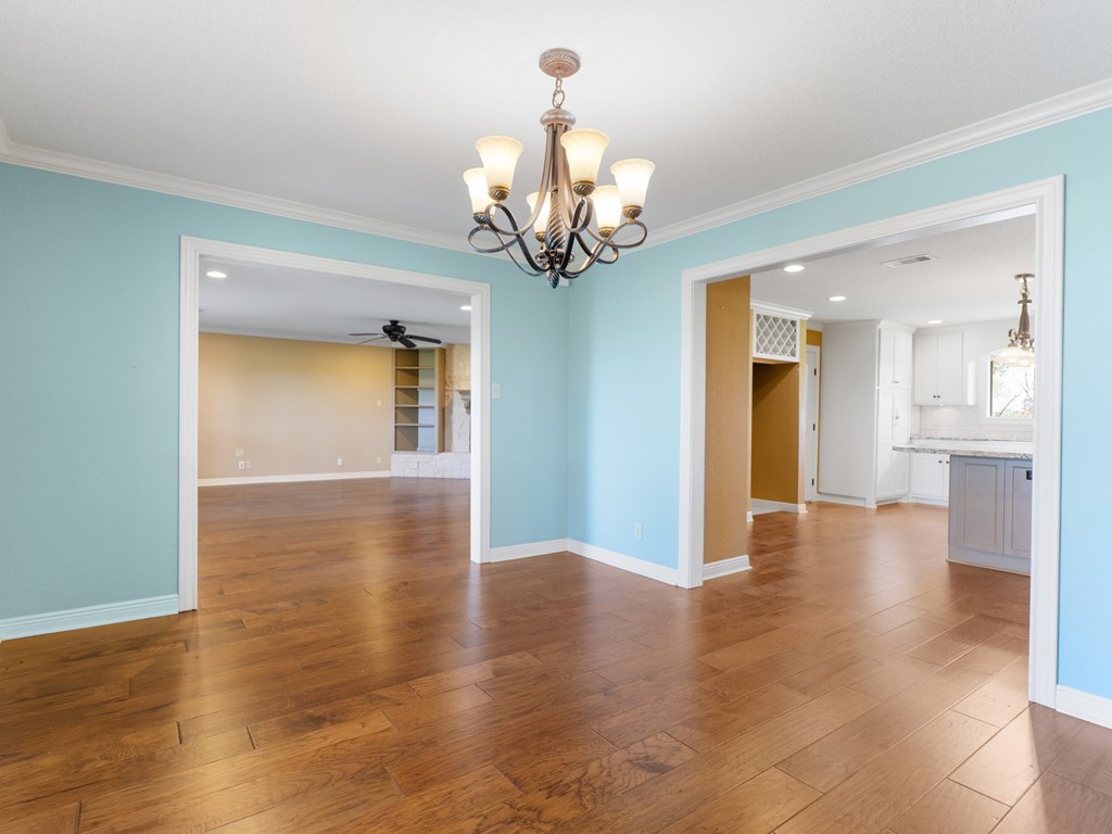 A room with a chandelier and hardwood floors.
