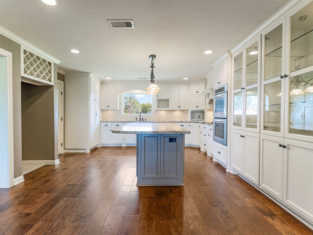 A kitchen with wooden floors and white cabinets.