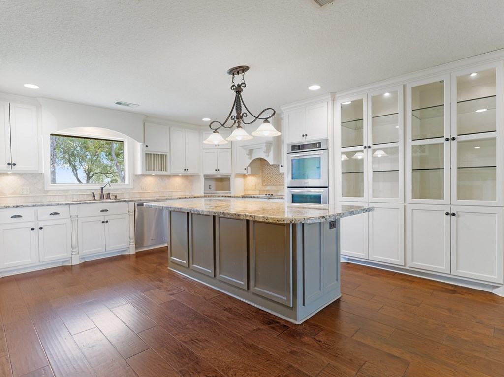 A kitchen with a large island and wooden floors.