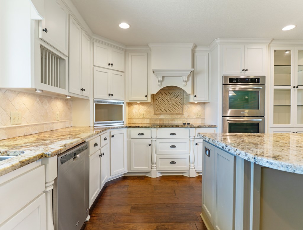 A kitchen with white cabinets and a marble countertop.