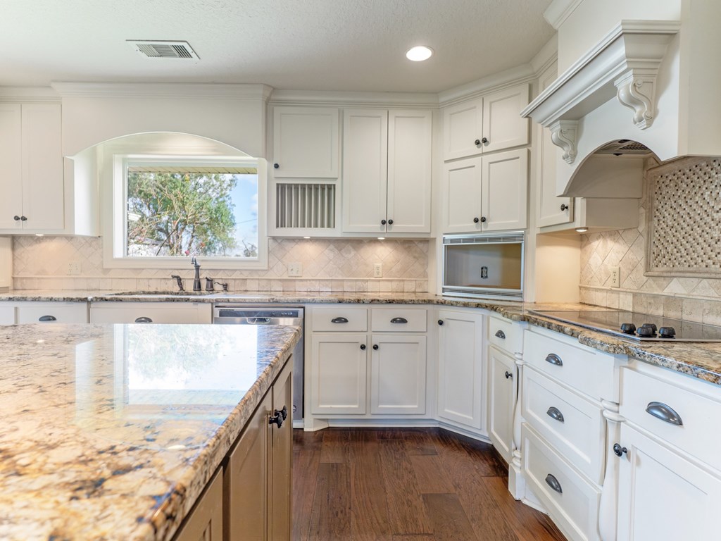 A kitchen with white cabinets and a granite countertop.