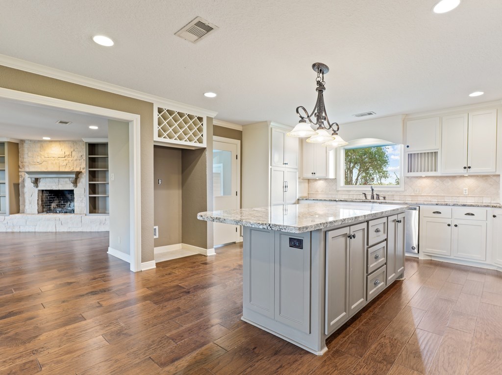 A kitchen with white cabinets and a marble countertop.