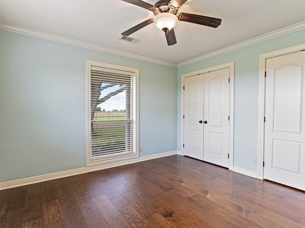 A room with a ceiling fan and wooden floors.