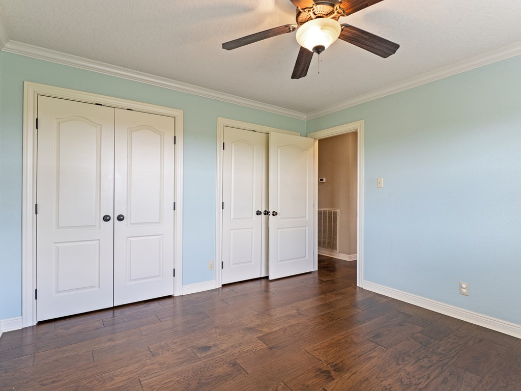 A room with a ceiling fan and three doors.