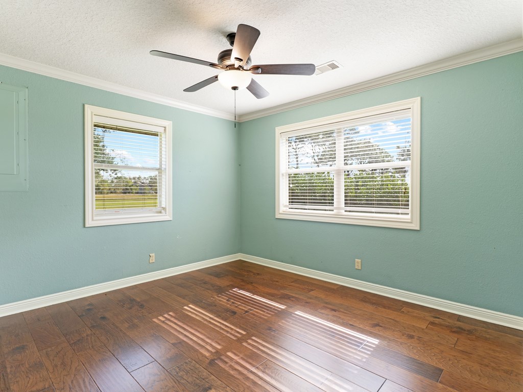 A room with a ceiling fan and two windows.