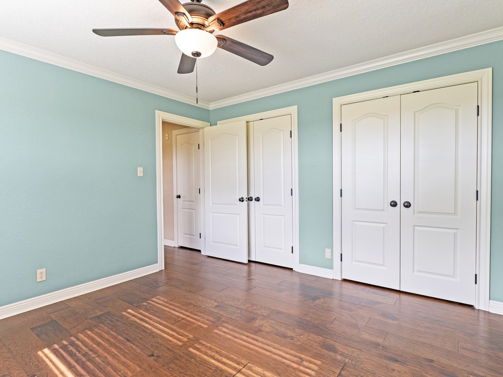 A room with a ceiling fan and four doors.