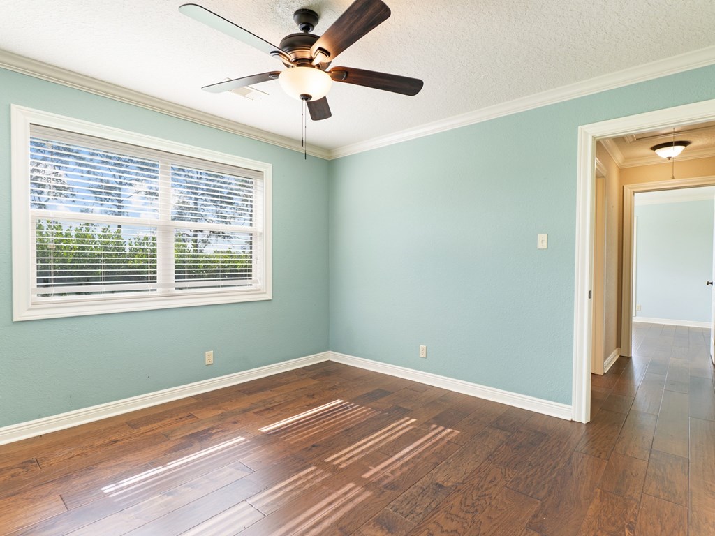 A room with a ceiling fan and a window with blinds.