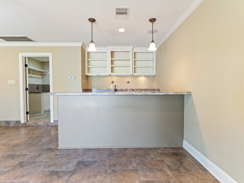 A kitchen with a marble countertop and a tile floor.