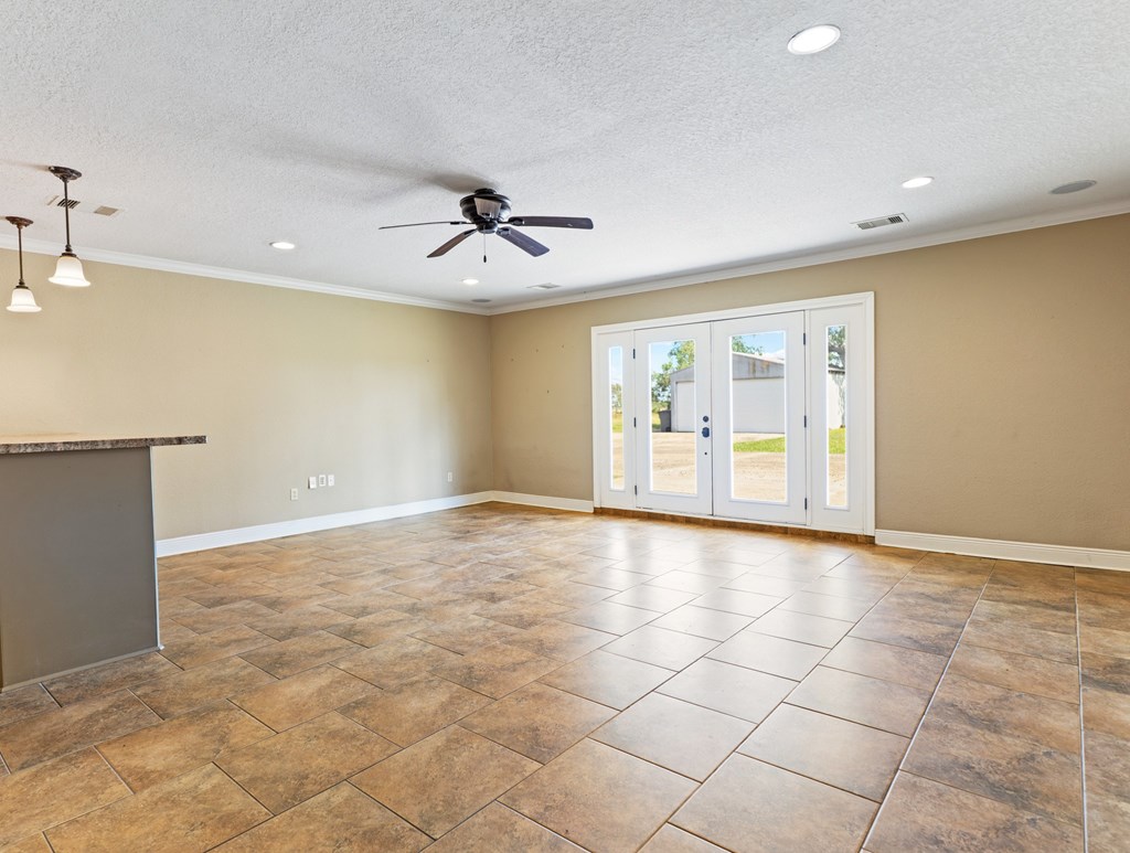 A room with a ceiling fan and sliding glass doors.