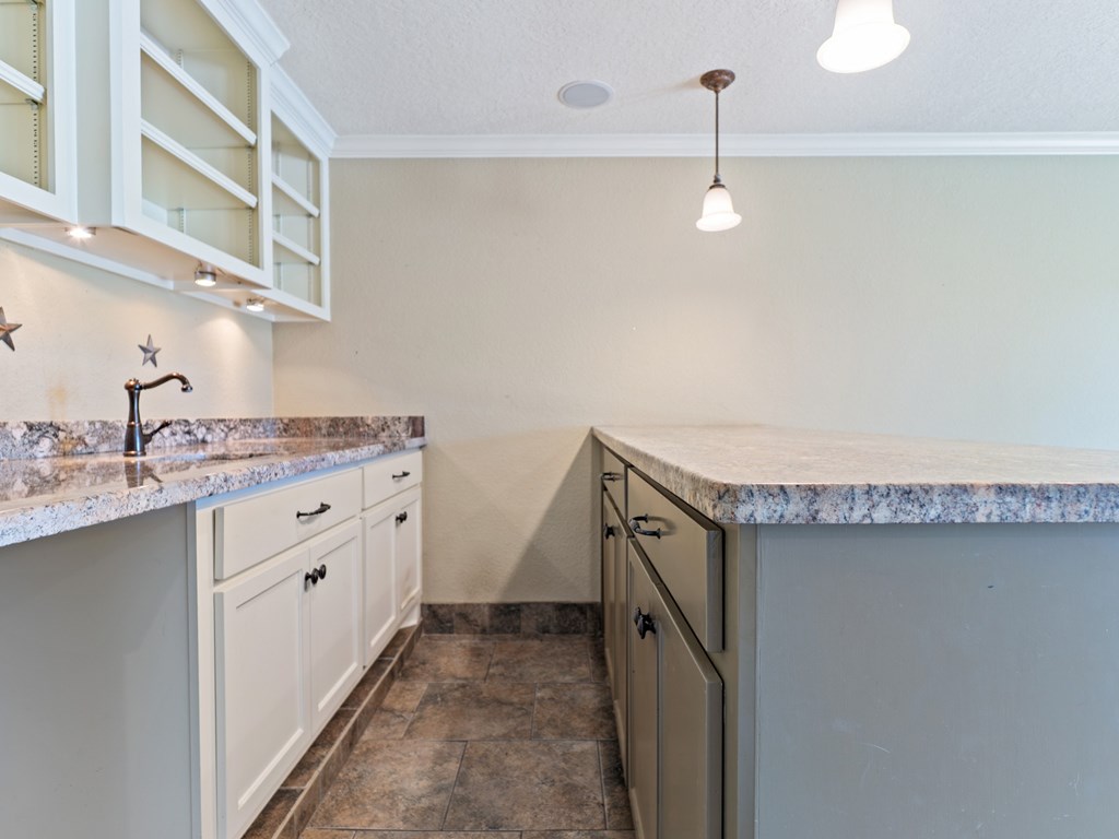 A kitchen with a marble countertop and white cabinets.
