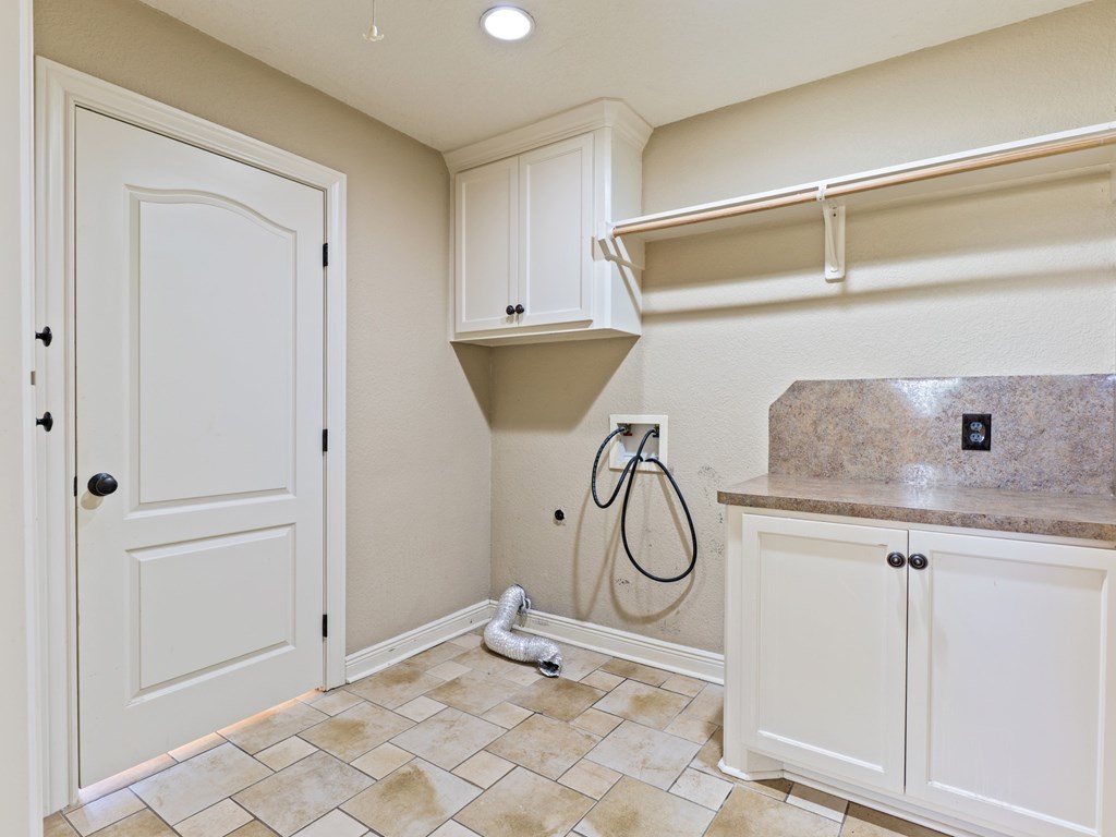 A bathroom with a white door, a tiled floor, and a marble countertop.