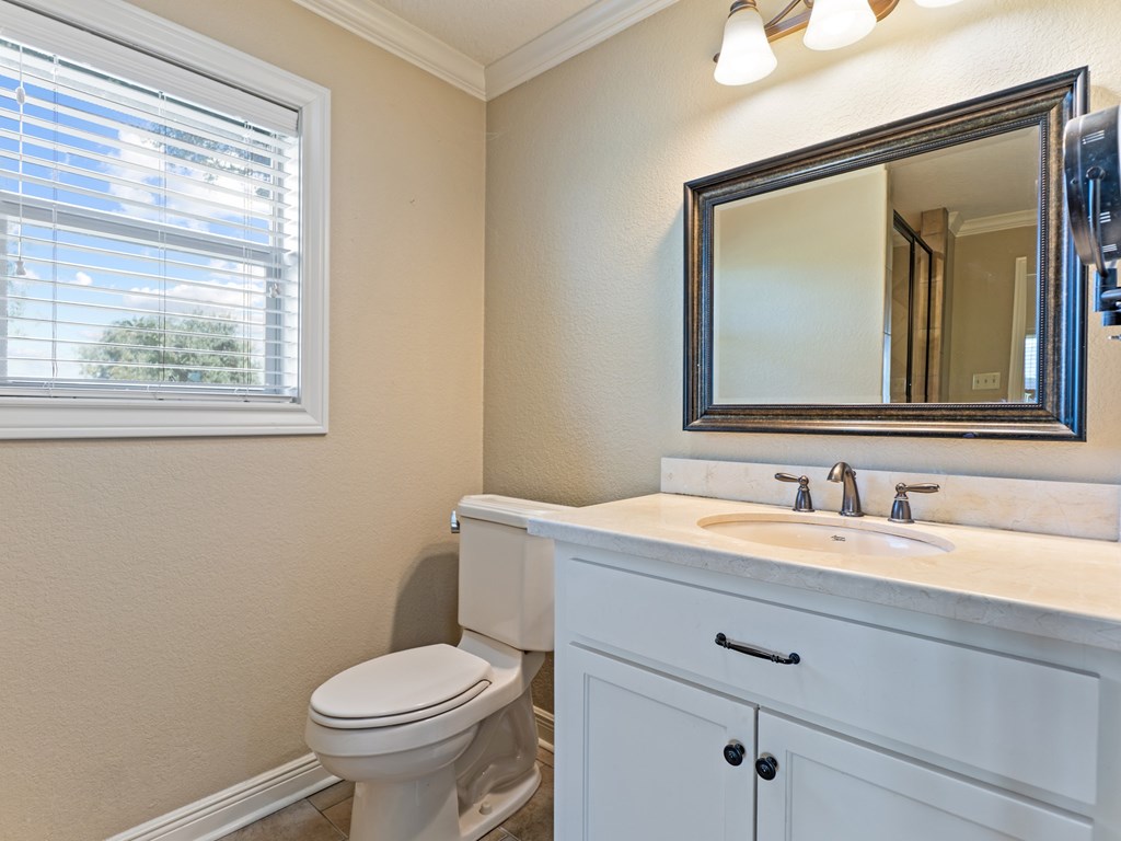 A bathroom with a toilet, sink, and mirror.