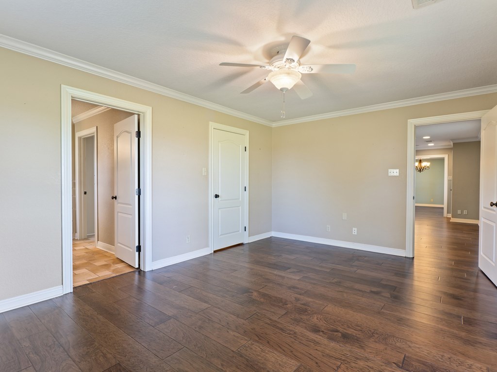 A room with a ceiling fan and wooden floors.