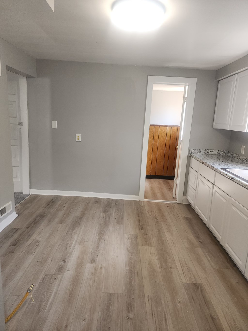 A kitchen with white cabinets and a wooden door in the background.