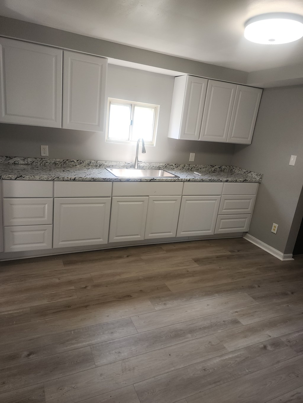 A kitchen with white cabinets and a marble countertop.